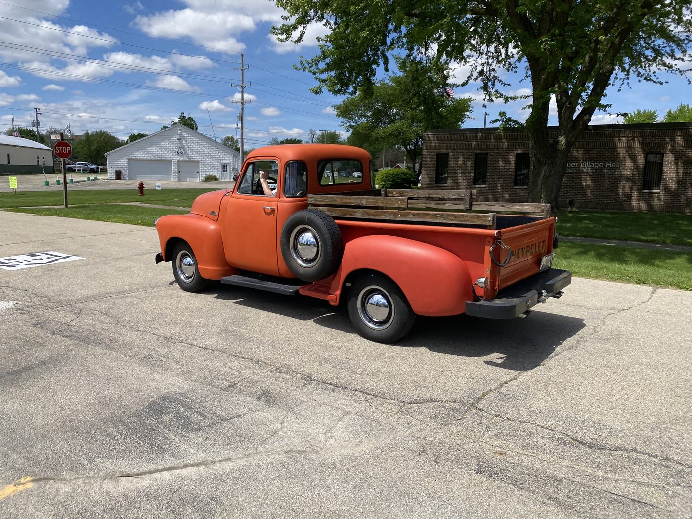 Classic orange Chevrolet pickup truck driving past Gardner Village Hall and Fire Department